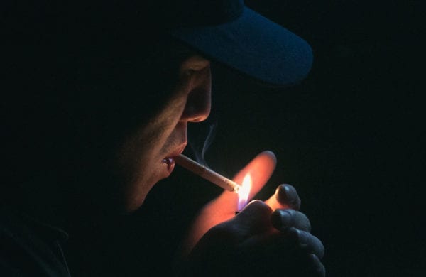 man lighting a cigarette in the dark