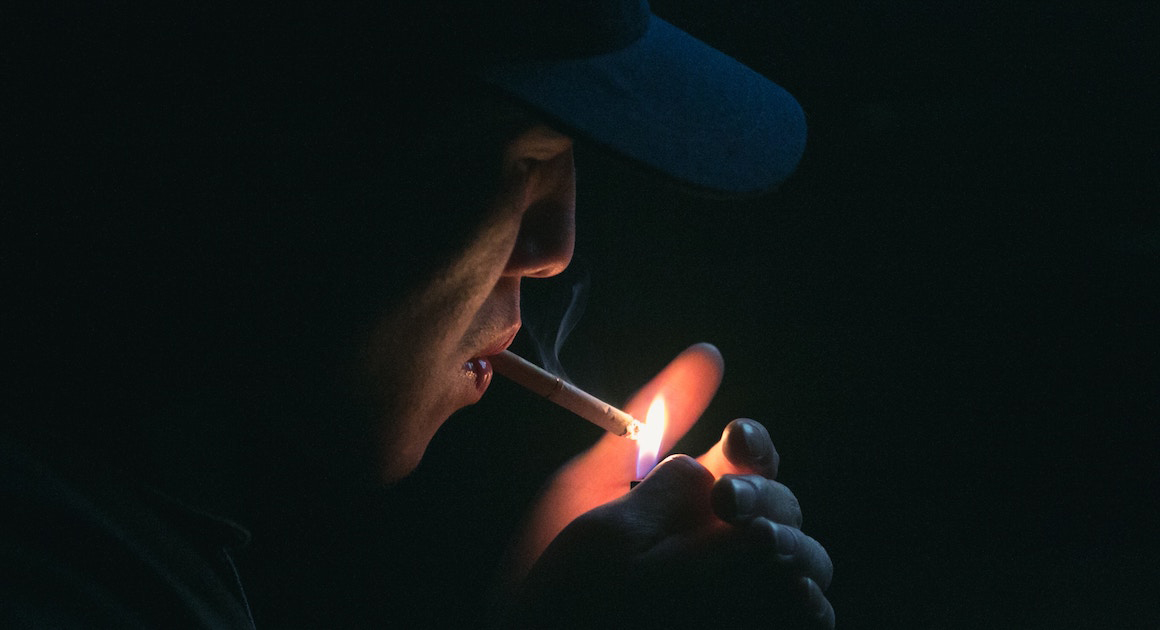 man lighting a cigarette in the dark