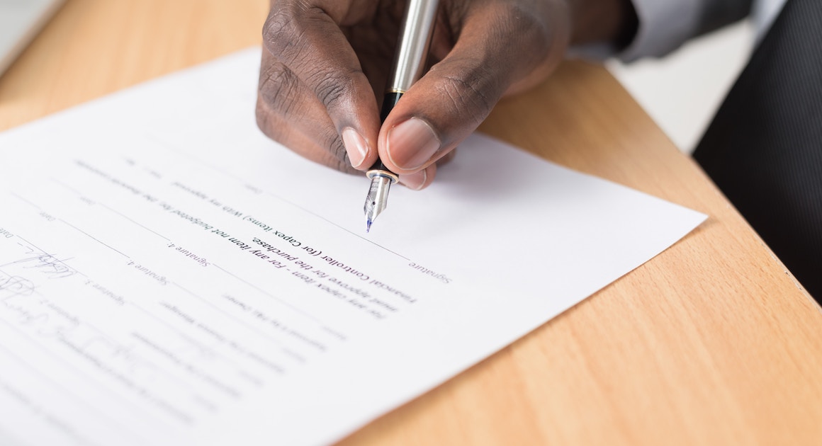 hand signing a contract with a pen