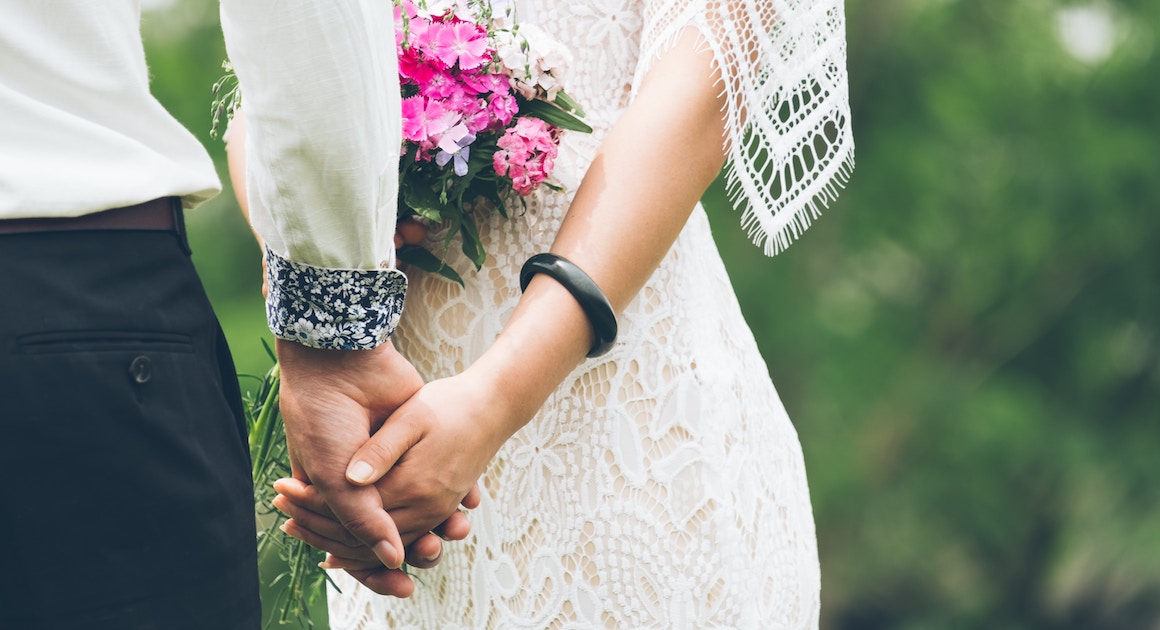 bride and groom holding hands with flowers