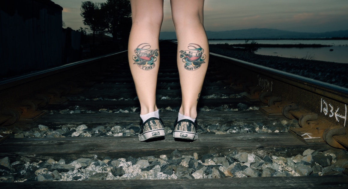 woman facing away on train tracks with tattoos
