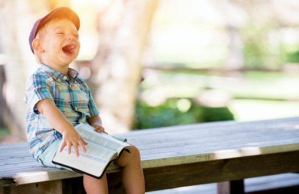 a child laughs holding a book
