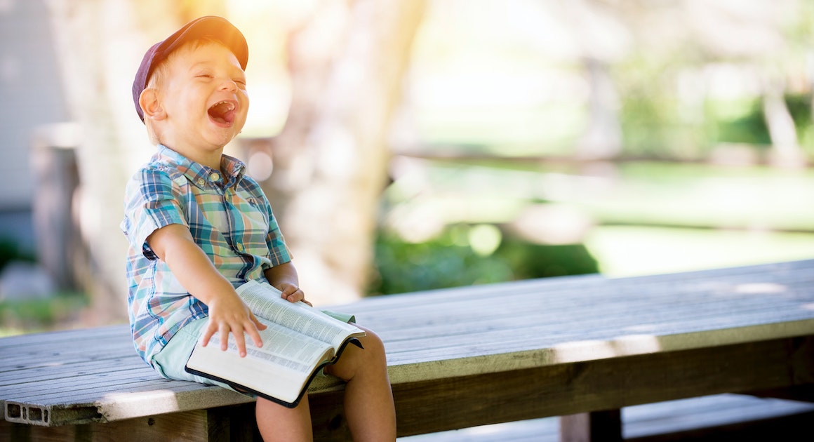 a child laughs holding a book