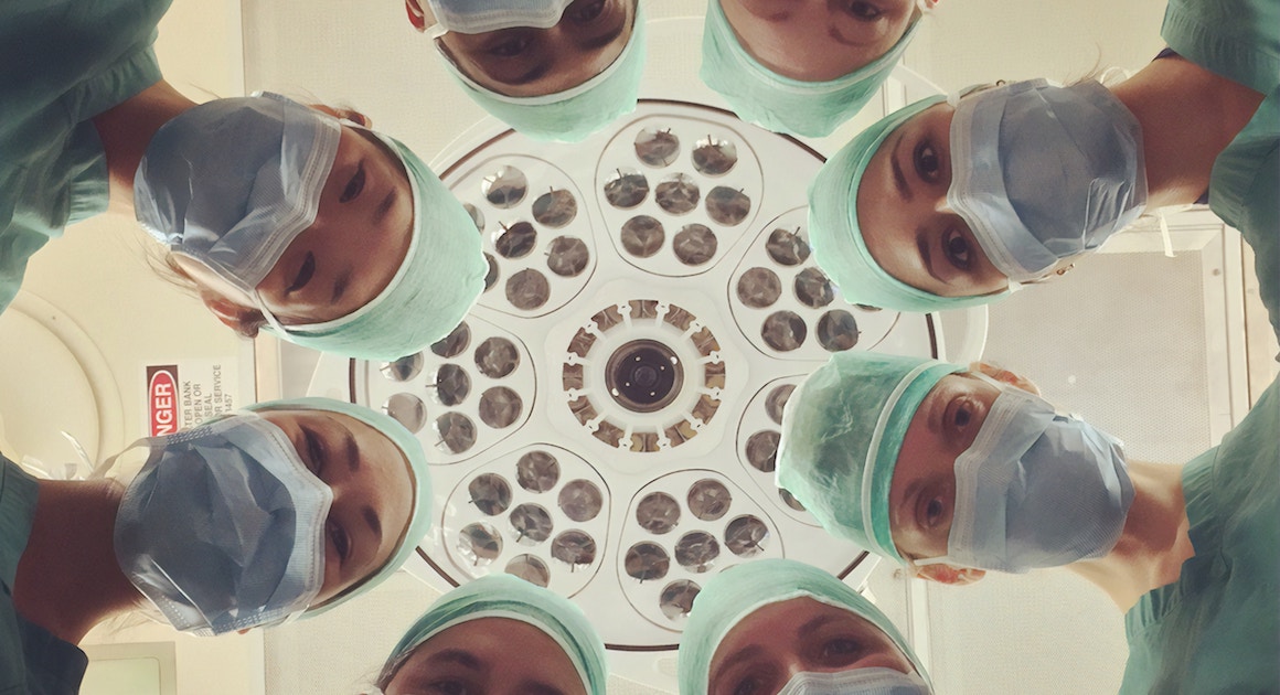 doctors in a circle looking down at a patient