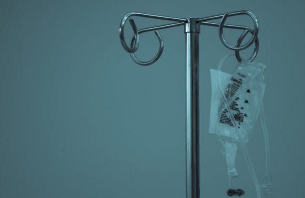 an empty IV bag hangs from a pole