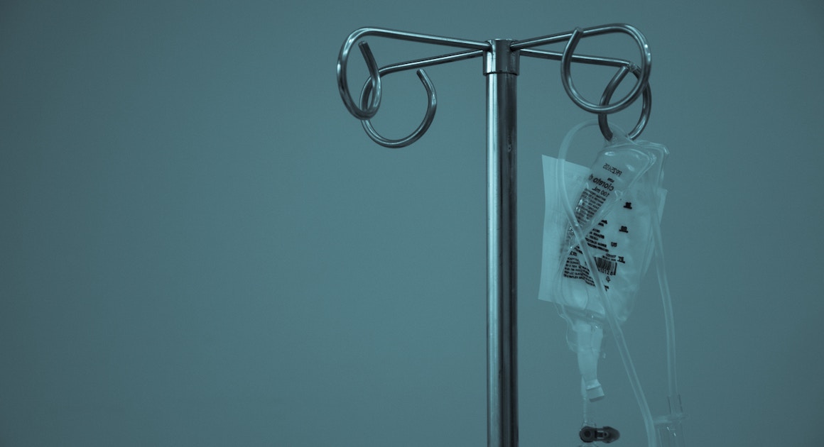 an empty IV bag hangs from a pole