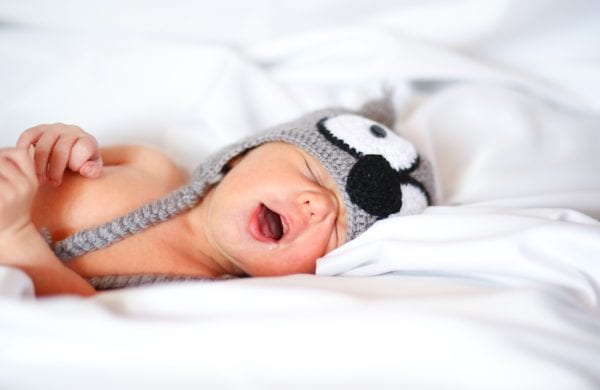 snoring infant wearing a hat in bed