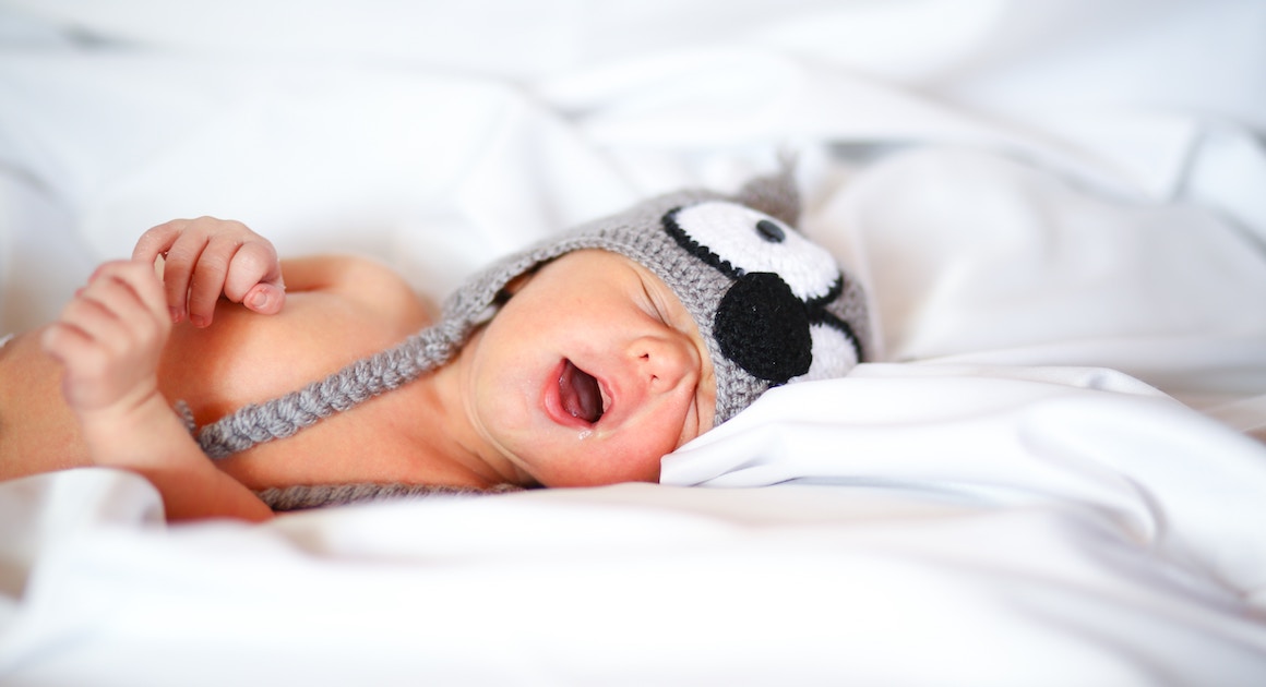 snoring infant wearing a hat in bed