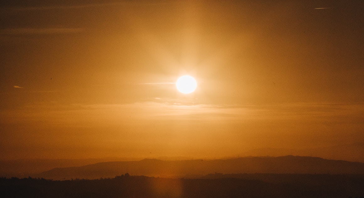 the sun rises above distant mountains