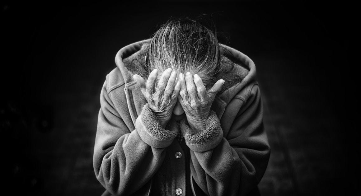 an old woman holds her head in her hands