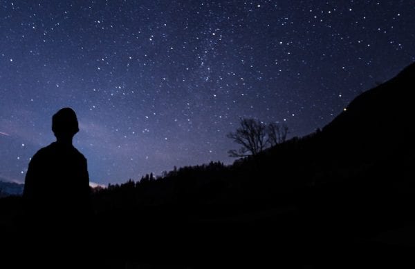 man in silhouette looking at the night sky