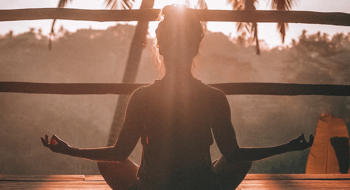 a woman mediates facing the sun