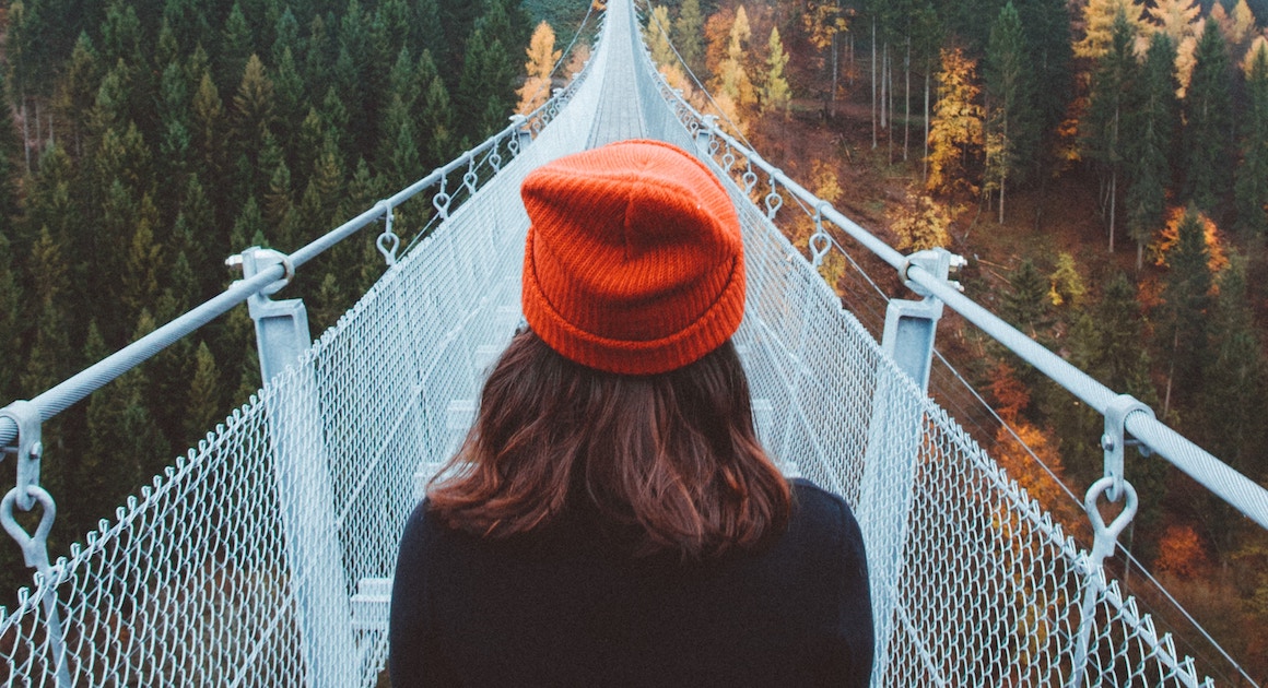 a woman looks out over a narrow bridge