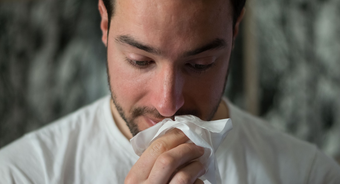 man wiping his nose with a tissue