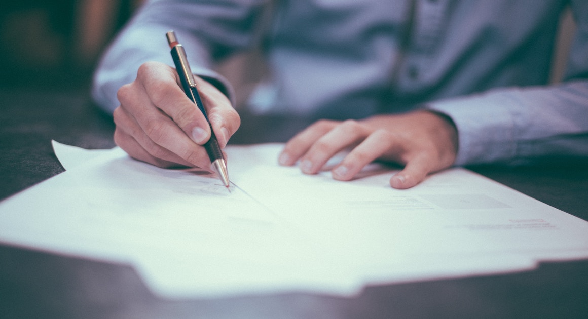 signing a document with a pen