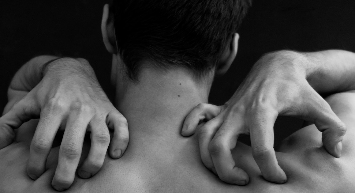 man digging into his shoulders with his hands