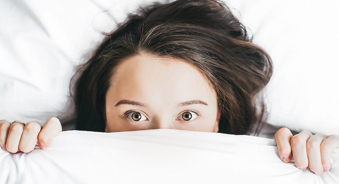 woman hiding under covers